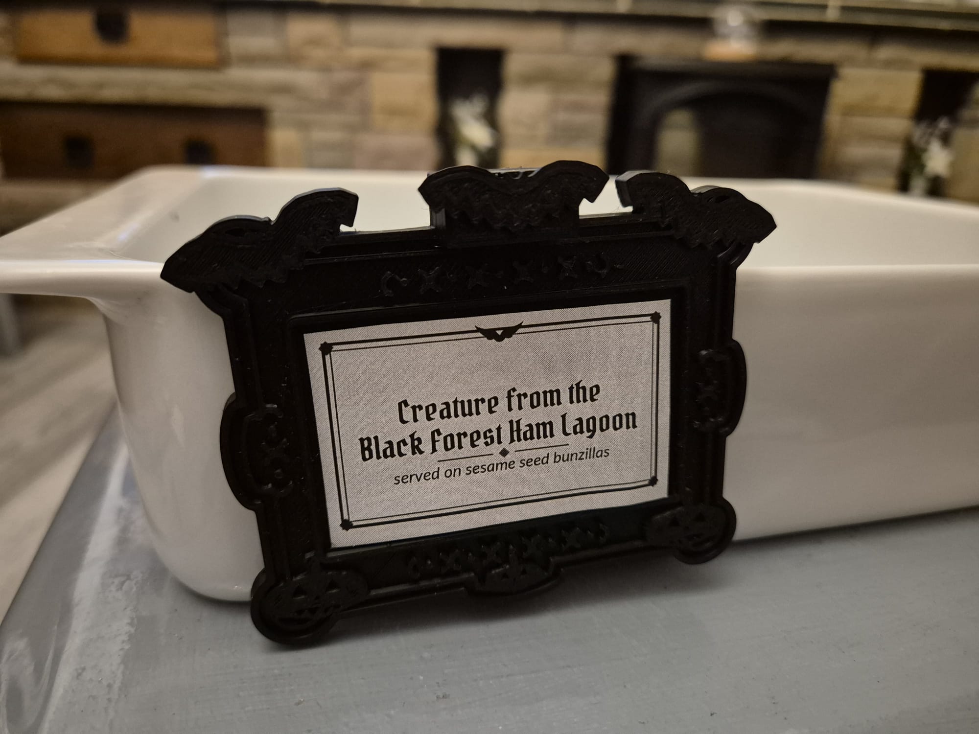 Bats and pumpkins tag reading "Creature from the Black Forest Ham Lagoon" on a white ceramic dish