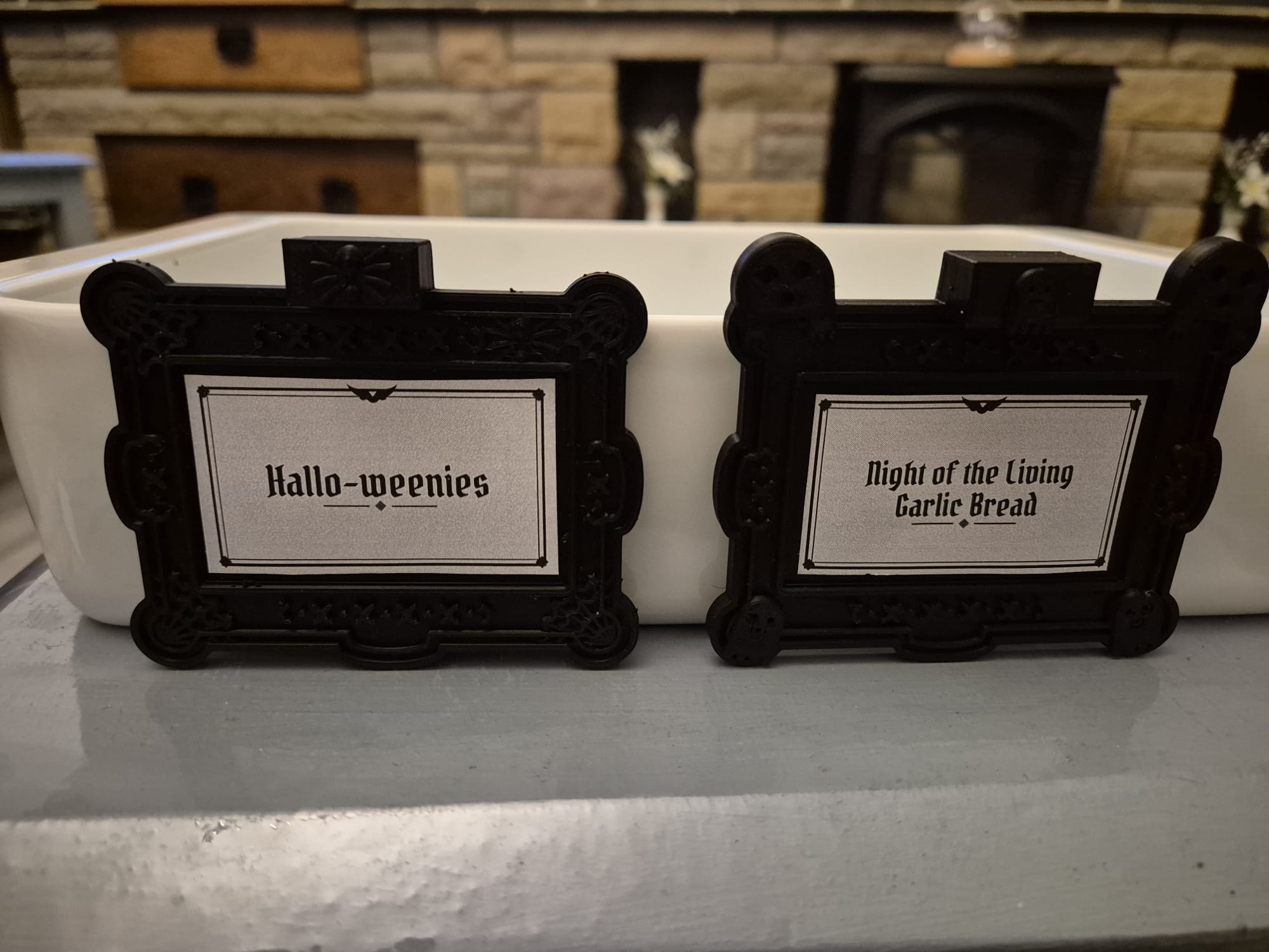 Two tags, "Hallo-weenies" and "Night of the Living Garlic Bread", side by side on a white ceramic dish
